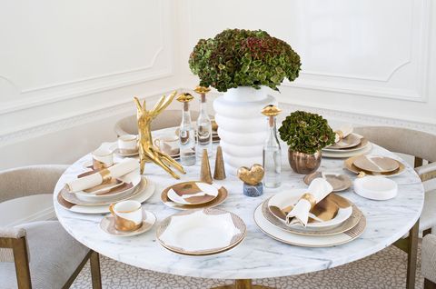 a marble table with gold and beige plates napkins and accessories