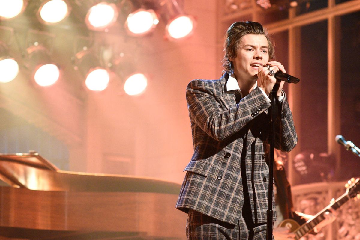 Harry Styles wearing a checkered suit performing on SNL