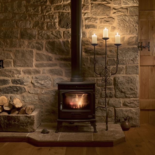 Wood burning stove and logs in a cottage living room.