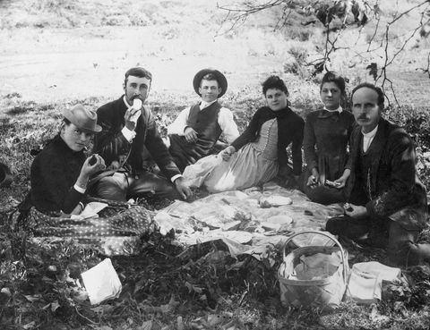 1890s 1900s GROUP OF SIX PEOPLE SITTING AROUND AN OUTDOOR PICNIC SPREAD ON THE GROUND LOOKING AT CAMERA