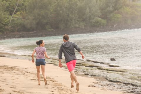 Young couple enjoy a walk along on beautiful sandy Hawaii beach
