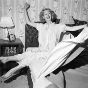 1950s SMILING HAPPY GLEEFUL WOMAN WAKING UP GETTING OUT OF BED FLINGING BACK SHEETS AND BLANKETS