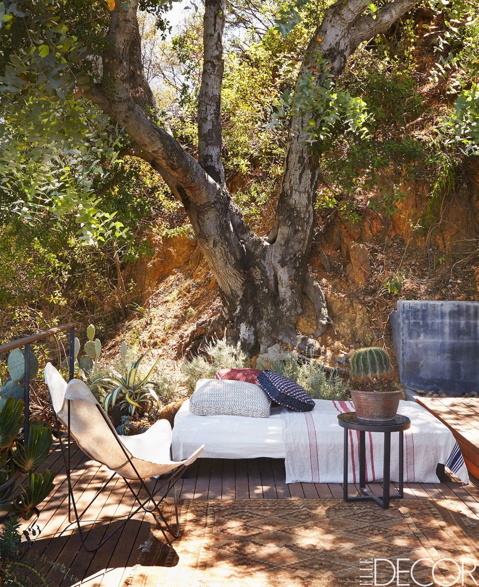 La diseñadora de moda Rozae Nichols ha mantenido un estilo rústico sofisticado en el porche de su casa midcentury de Laurel Canyon (Los Ángeles). Los cojines son de Gregory Parkinson, y la cama de día, de Van Keppel-Green. Sobre ella, una toalla turca a modo de colcha.
  