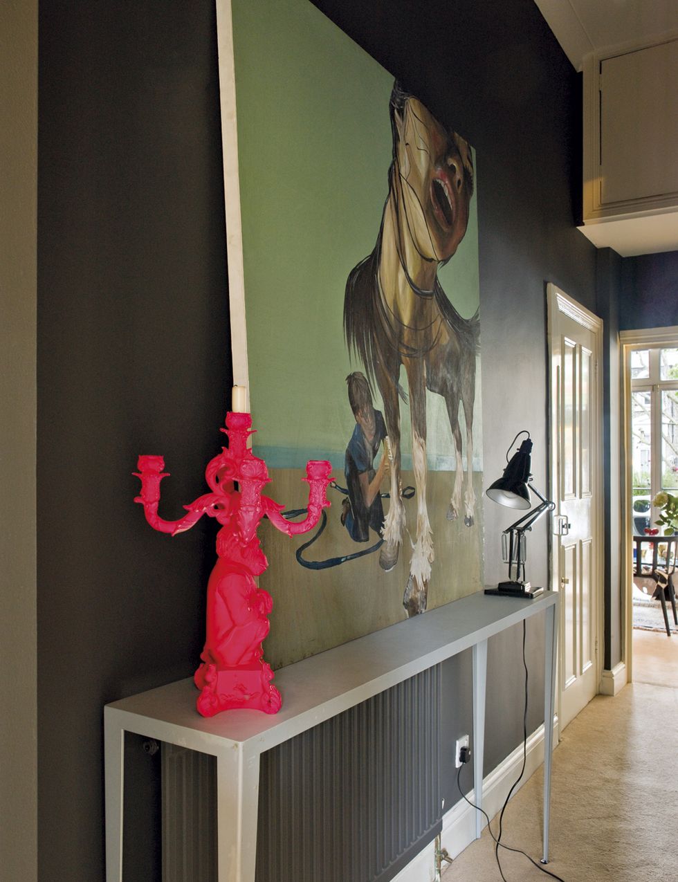 <p>Un candelabro con silueta de mono, de Seletti, pintado con spray en rosa neón para dar un toque &quot;dramático&quot; nos recibe. La mesa metálica es de una tienda en París, y el flexo, de Anglepoise.</p><p>&nbsp;</p>