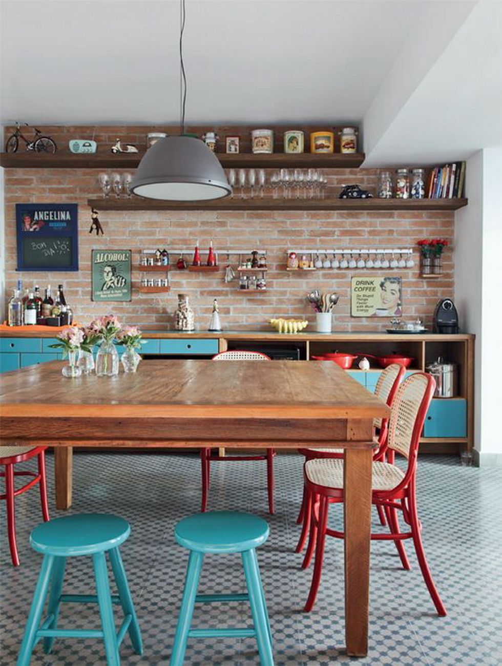 <p>Con un frente de ladrillo y un pavimento de efecto geométrico, esta cocina destaca por su alegre comedor, con las clásicas sillas Thonet customizadas en rojo y unos taburetes pintados de azul turquesa.</p>