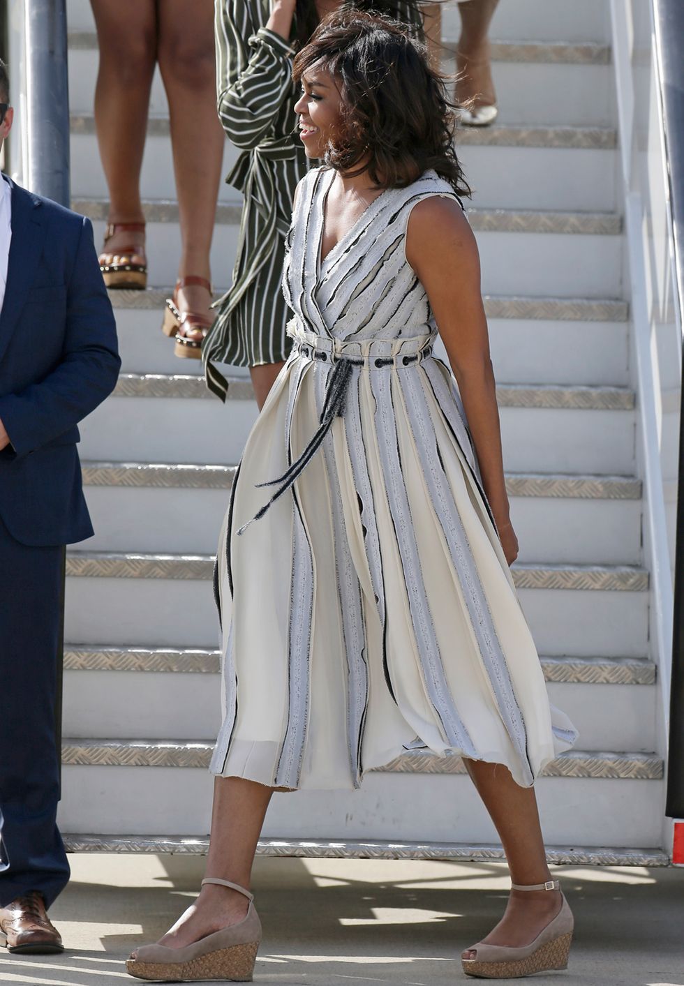 <p>En su llegada al aeropuerto de Torrejón de Ardoz Michelle Obama eligió un vestido midi con estampado de rayas y unas cuñas peep toe con pulsera.</p>