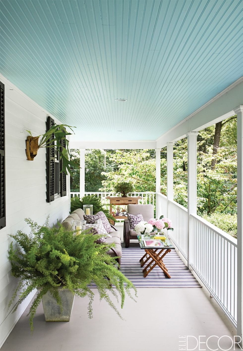 El tono Glacier Blue, de Benjamin Moore, ha sido  el elegido para dar vida al techo de este porche de Connecticut, propiedad del diseñador Philip Gorrivan. Alfombra, de Dash & Albert.