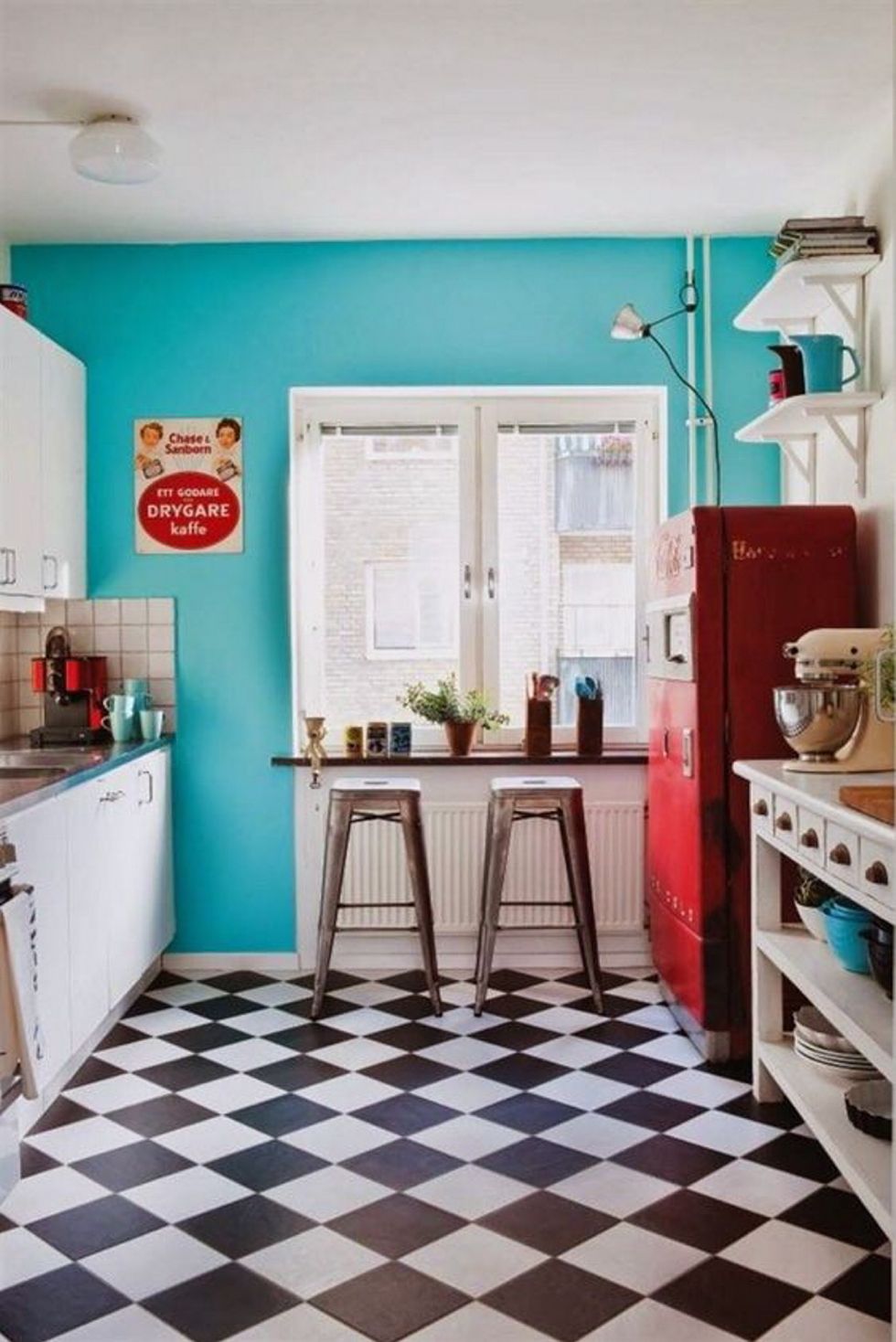 <p>Todo un clásico de las cocinas vintage, se alegre con la pared pintada de azul turquesa y el frigorífico rojo. Los taburetes metálicos son el mod. <i>Tolix.</i></p>