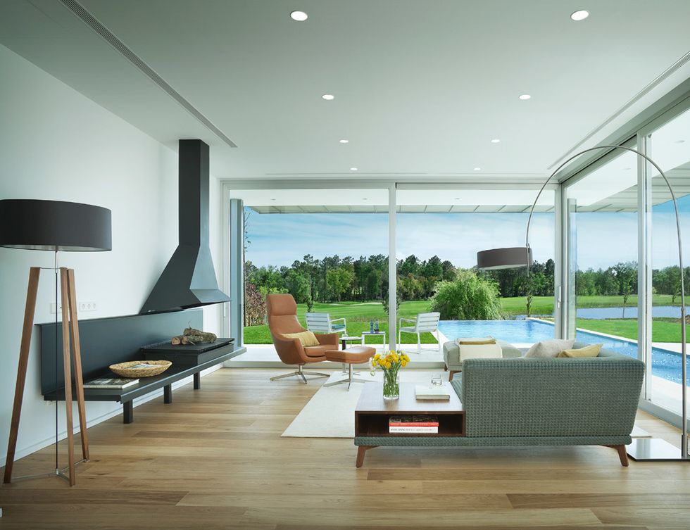 <p>Las paredes de cristal comunican los distintos espacios de la casa con el jardín. Con muebles de diseño actual, el salón resulta de lo más acogedor gracias a la chimenea central.&nbsp;</p>