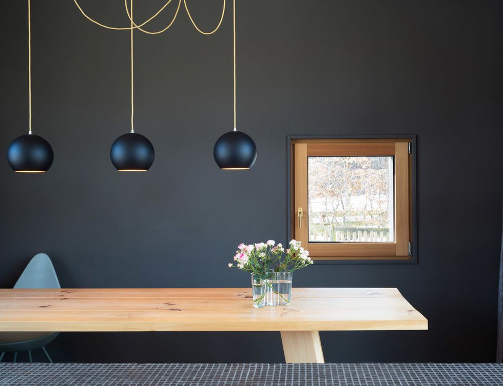 <p>Con pared y lámparas en color negro, que contrastan con el tono natural de la mesa de madera.</p>