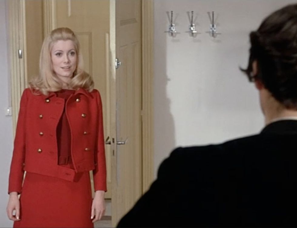 <p>Catherine Deneuve vistió durante toda la película maravillosos trajes de un jovencito Yves Saint Laurent, con el que establecería una estrecha relación de amistad. ¡Cómo olvidar este precioso vestido en dos tonos de rojo, a juego con una chaqueta Eisenhower de doble botonadura!</p>