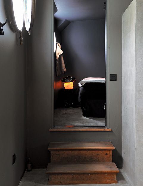 Desde la cocina, unas escaleras de madera conducen a uno de los dormitorios para huéspedes, iluminado por un espectacular ojo de buey.