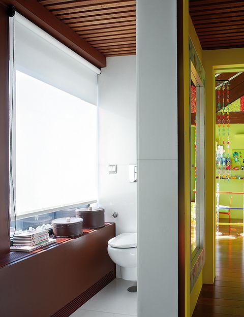  <p>El baño en blanco y madera constrasta con la habitación llena de color y espíritu infantil.</p>