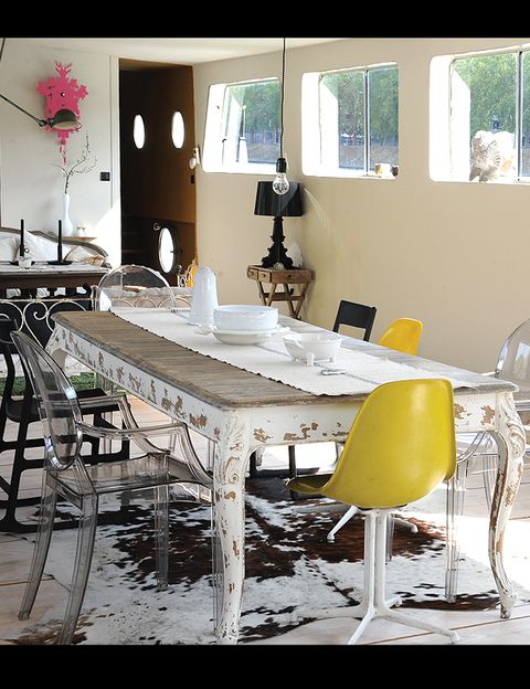 En torno a la mesa de comedor, una pieza antigua encontrada en el mercadillo anual de Rennes, se combinan sillas Louis Ghost, de Philippe Starck para Kartell, con mecedoras de Ikea y unas sillas amarillas recuperadas. Debajo, una alfombra de vaca.