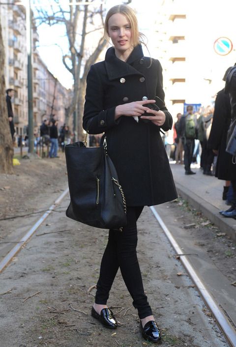 <p>Esta modelo luce un look total black (móvil incluido) con un maxi bolso con detalles dorados y zapatos de charol.</p>