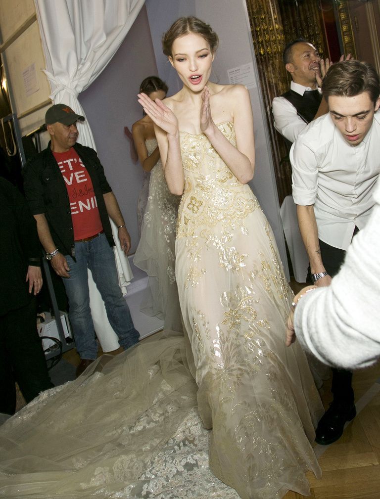 <p>...pero antes de salir a escena, la modelo se anima dando palmas y ánimos a los que la ayudan a colocar el vestido.</p>