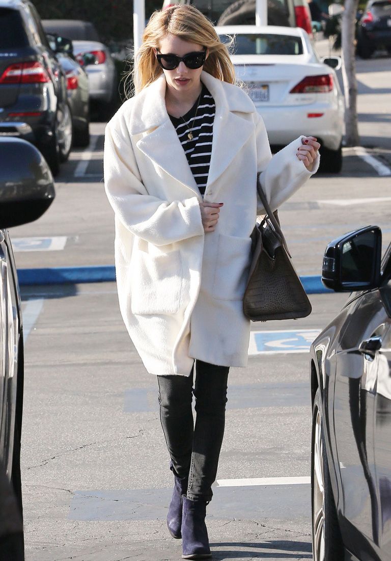 <p><strong>Emma Roberts</strong> apuesta por un abrigo blanco oversize, camiseta navy, pitillos en gris, botines morados y bolso de piel negro.</p>