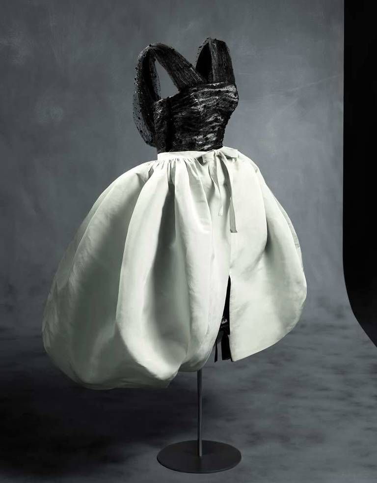 <p>Este vestido se presentó en la colección de <strong>Balenciaga</strong> de invierno de 1956 y tiene todas las características que definen la silueta típica de los años 50: corsé, gran escote y amplio vuelo en la falda.</p><p>Un vestido que además, aportó una gran novedad: la pieza exterior, que sirve como capa o como sobrefalda.</p>