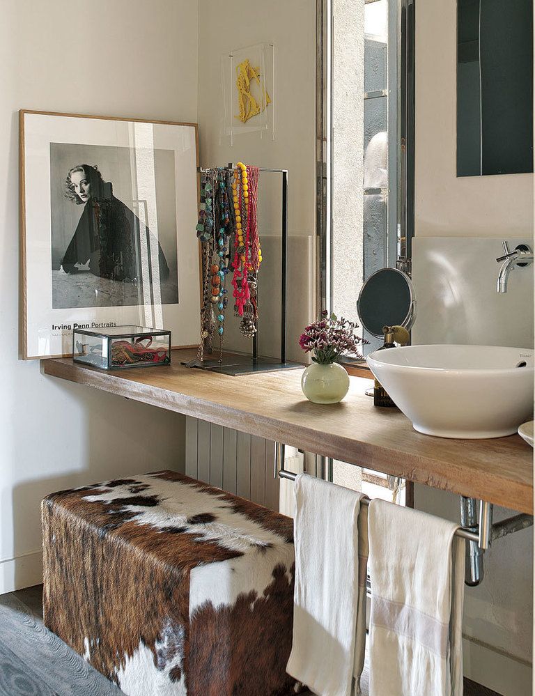 <p>Ciertos detalles, como collares y accesorios colgados, y la fotografía de Irving Penn, crean una atmósfera femenina en el baño. El lavabo exento es de la firma Duravit y se apoya en una encimera de madera tratada.</p>