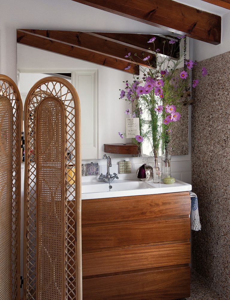 <p>Detrás del biombo de bambú  se encuentra el precioso baño,  en el que destaca la pared de mosaico de guijarros. Los floreros son unas botellas de cristal.</p>