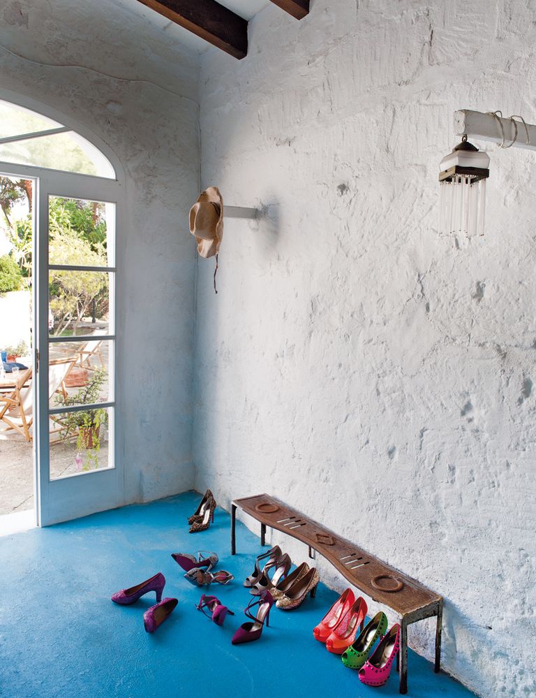 <p>Varios zapatos de la colección primavera/verano 2013 de Mascaró se han colocado bajo un protector de chimenea de hierro reconvertido en banco para descalzarse. El pavimento  de cemento se ha pintado de azul en un  claro guiño al espíritu marinero de la zona.</p>