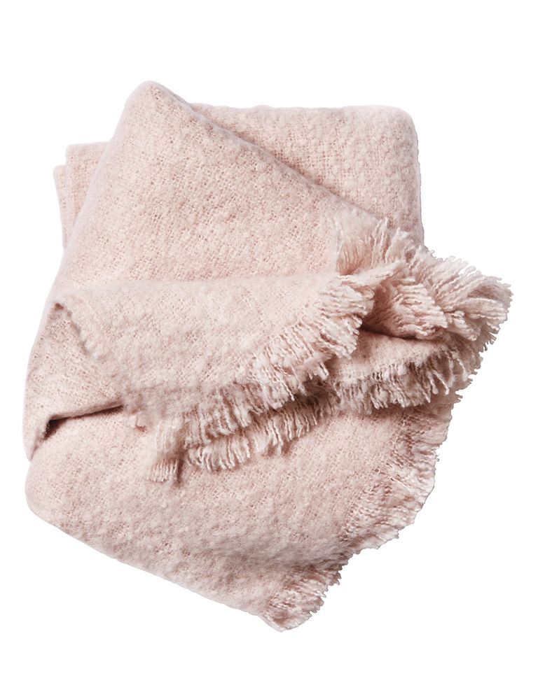 <p>Manta en tejido  bouclé aterciopelado  con flecos, de H&amp;M Home.</p>