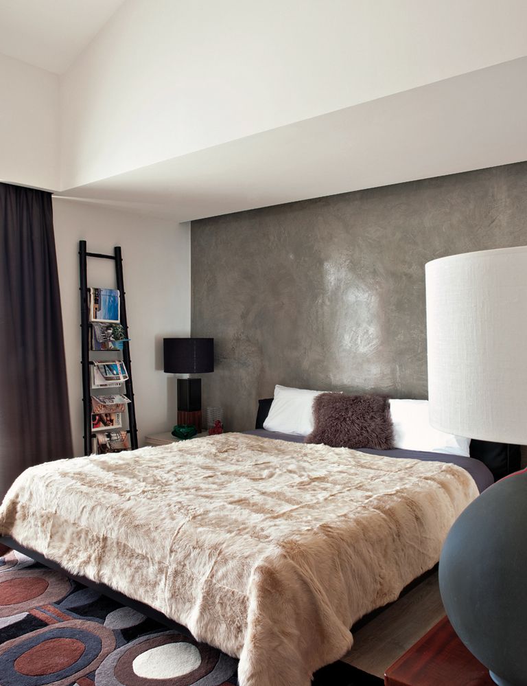 <p>Abrigan con estilo  el dormitorio principal, presidido por una cama, de Pianca, con cabecero de piel. El revistero es una escalera de bambú negro procedente de Bali, y la alfombra, en tonos grises y tostados, es el modelo <i>Capri,</i> de Carpet Diem</p>