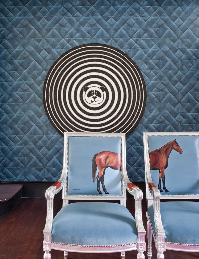 <p>Una de las paredes, revestida con el papel pintado <i>Mis en Plis</i> en azul, de la colección <i> Pleats,</i> de Élitis, exhibe la obra <i>Hypnotic Panda,</i> del artista pop Rob Pruitt. Delante, las butacas <i>Blue Horse,</i> pintadas a mano, de Jimmie Martin.</p>
