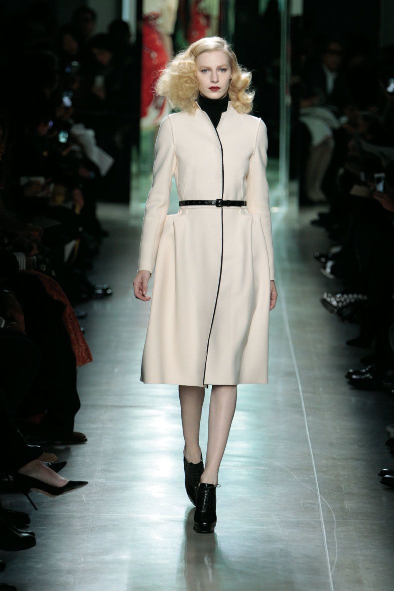<p>Abrigo de estilo 'fifties' en tono blanco roto con un fino cinturón potenciando la figura femenina.</p>