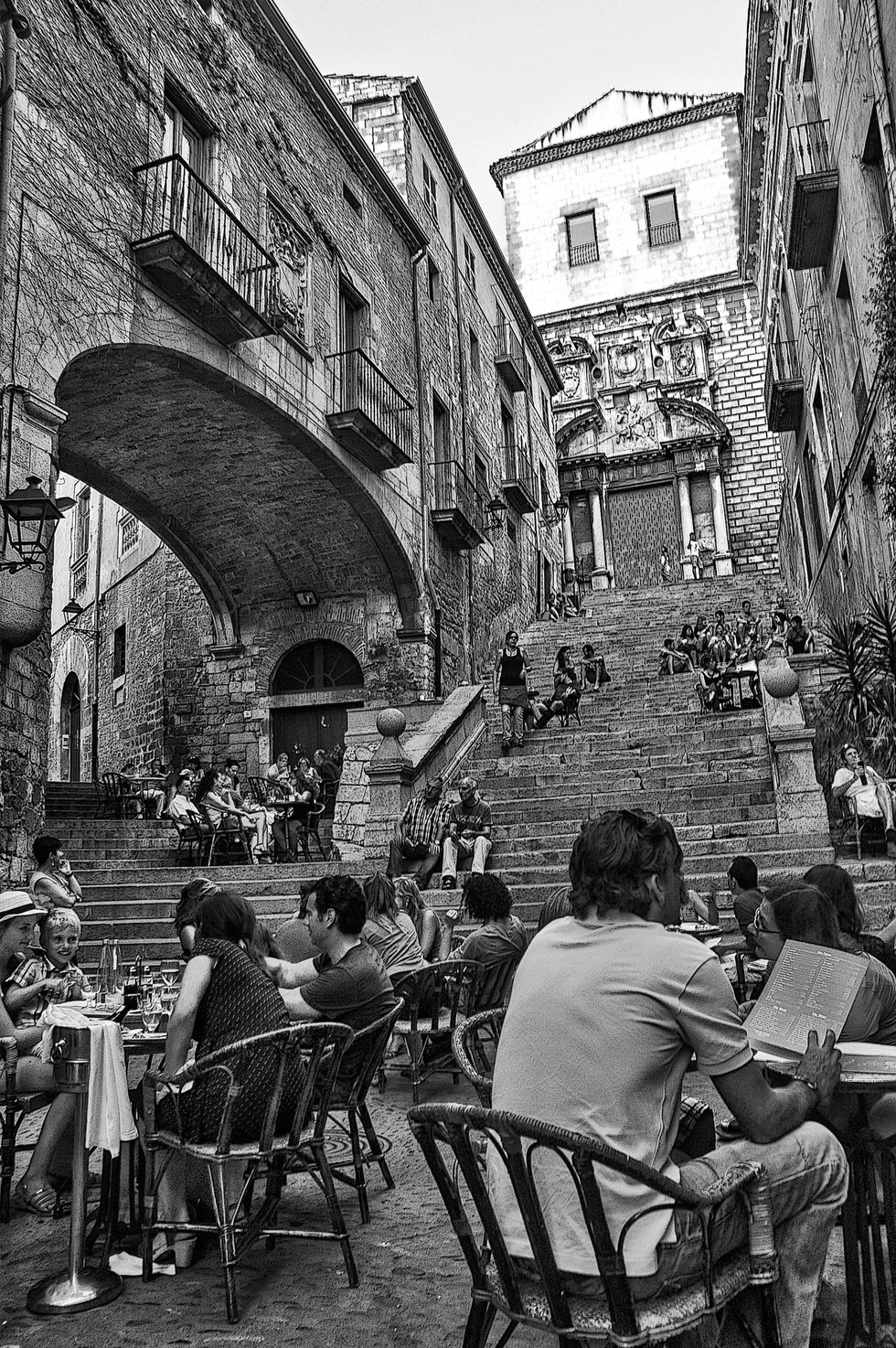 Human body, Sitting, Neighbourhood, Furniture, Chair, Table, Town, Street, Arch, Outdoor furniture, 