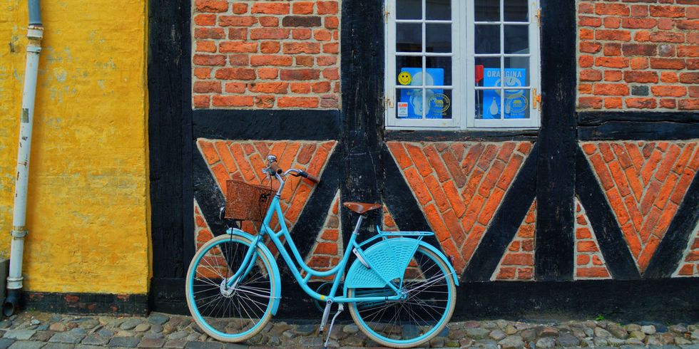 Bicycle wheel, Bicycle, Bicycle part, Wall, Blue, Orange, Mode of transport, Vehicle, Brickwork, Spoke, 
