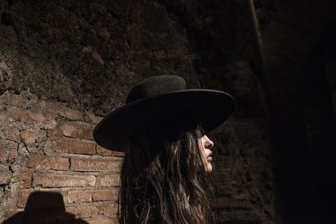 Hat, Darkness, Headgear, Fashion accessory, Costume accessory, Sun hat, Flash photography, Stone wall, Costume hat, Long hair, 