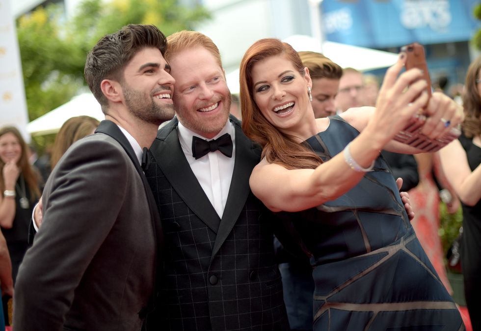 LOS ANGELES, CA - AUGUST 25:  66th ANNUAL PRIMETIME EMMY AWARDS -- Pictured: (l-r) Justin Mikita, actors Jesse Tyler Ferguson and Debra Messing take a selfie at the 66th Annual Primetime Emmy Awards held at the Nokia Theater on August 25, 2014.  (Photo by Jason Kempin/NBC/NBC via Getty Images)