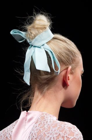 <p>Lo chignon alto di veste di poesia con un nastro azzurro chiuso a fiocco. Romanticismo moderno.</p>