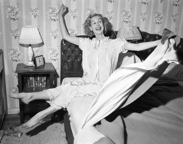 1950s SMILING HAPPY GLEEFUL WOMAN WAKING UP GETTING OUT OF BED FLINGING BACK SHEETS AND BLANKETS