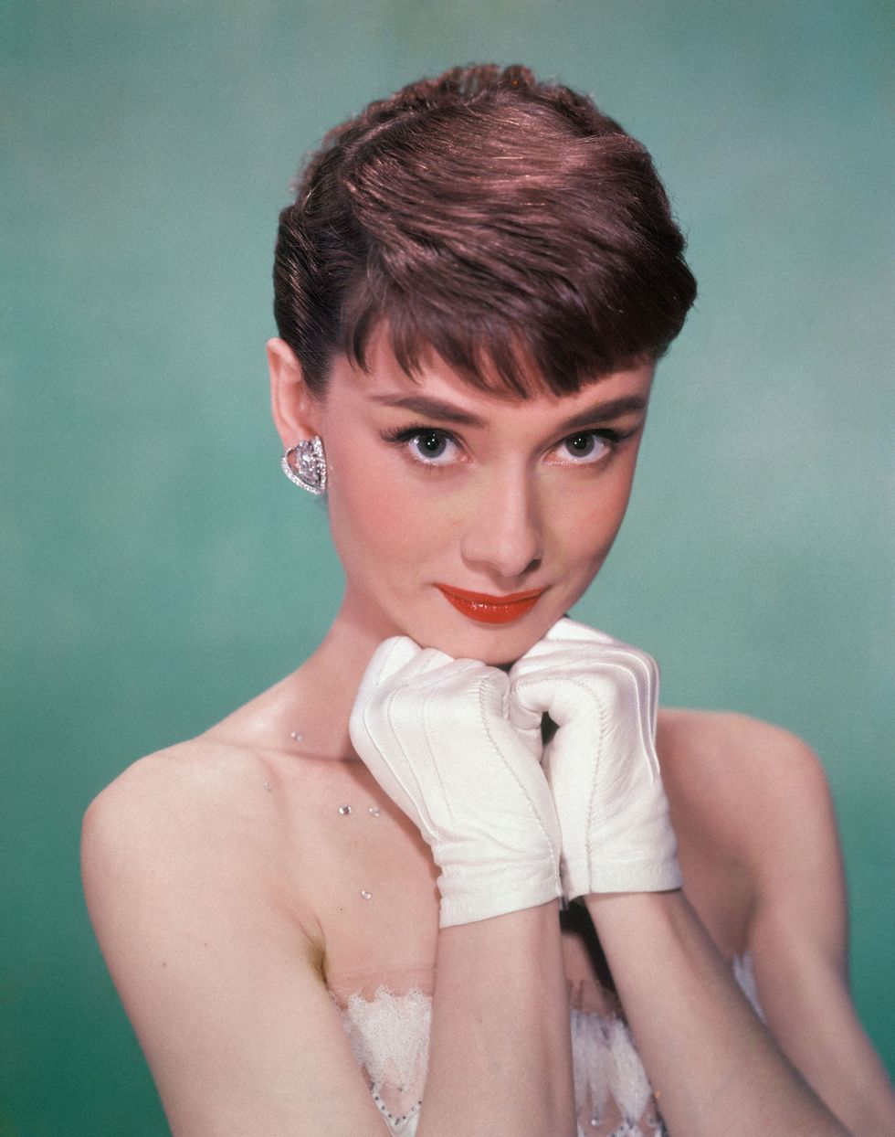 Portrait of Belgian-born American actress Audrey Hepburn (1929 - 1993) as she wears a strapless gown and holds white kid-gloved hands up to her chin, early 1950s. (Photo by Hulton Archive/Getty Images)