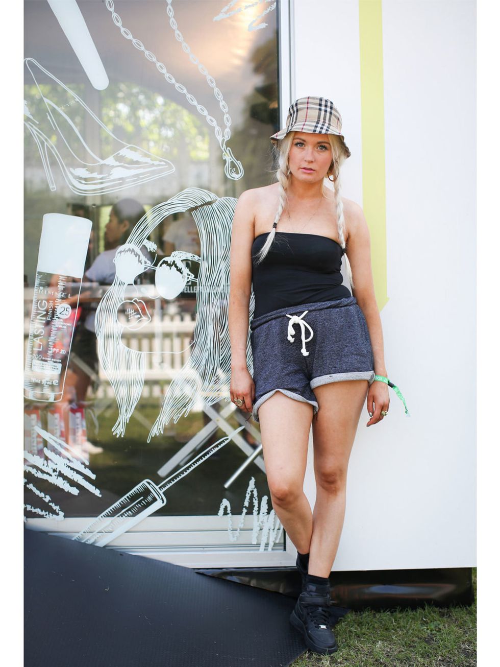 Lo wears Burberry Hat, H&amp;M top and shorts with Nike Air Force One trainers.