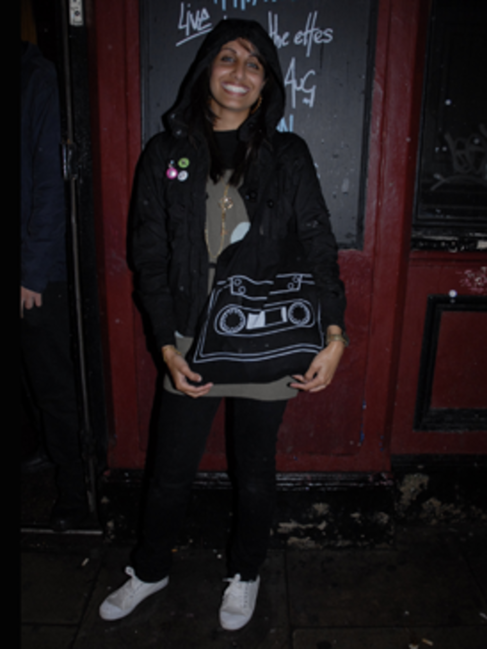<p>Saima's rocking the indie look with her kids H&amp;M black coat adorned with nu-rave bright button badges. Her cassette bag adds an element of fun and the black skinnies and white retro gym shoes finish off her perfect low key 'night down the pub' look