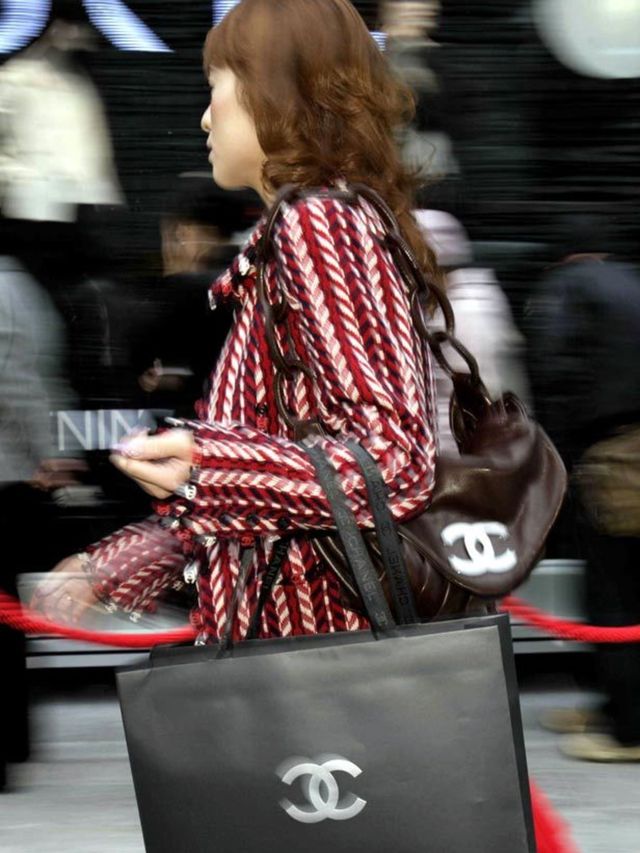 <p>Woman carrying a Chanel shopping bag</p>