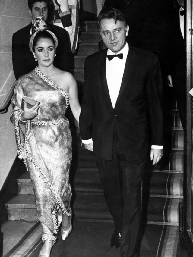 <p>Elizabeth Taylor in the Balenciaga 'Sari' gown with Richard Burton in 1964</p>