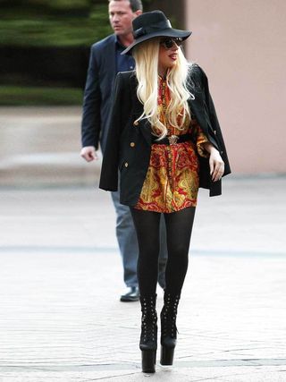 pLady Gaga chega aos fãs aos gritos em Melbourne usando um vestido estampado, casaco preto, chapéu e plataformas extra altas, Junho de 2012./p