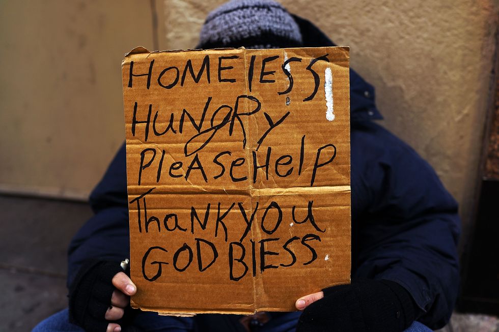 Homeless person holds up sign | ELLE UK