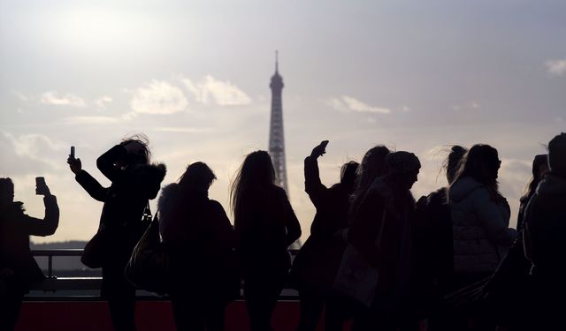 Silhouettes of people taking selfies with Eiffel Tower in the back. Image shot in Paris, France.