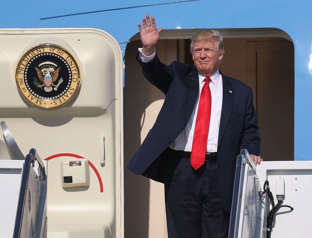 President Donald Trump waves as he arrives on Air Force One at the Palm Beach International Airport to spend part of the weekend at Mar-a-Lago resort.