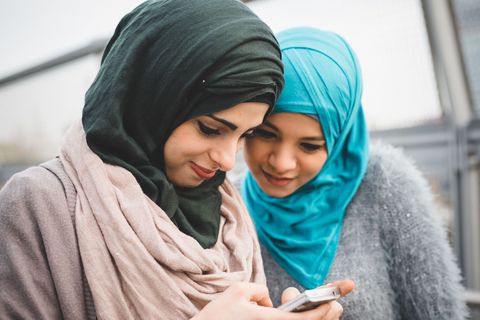 muslim women in headscarves looking at a phone