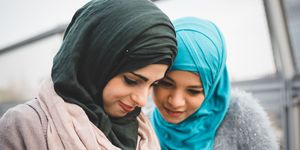 muslim women in headscarves looking at a phone