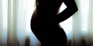 Pregnant woman by curtain window