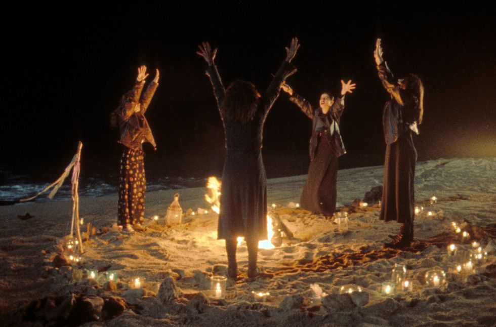 Robin Tunney, Fairuza Balk, Rachel True and Neve Campbell crowded around a fire, performing a ritual in a scene from the film 'The Craft', 1996.