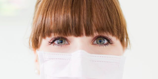 Woman with green eyes wearing a protective mask over her mouth