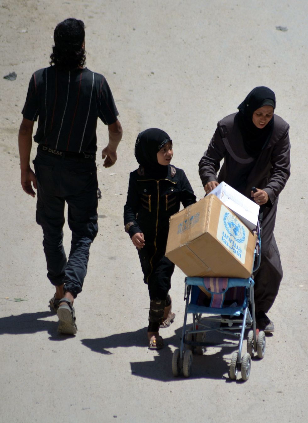 A woman uses a pram to transport a food aid parcel from UNWRA in the district of Yarmuk in southern Damascus on May 12, 2016, after they managed to access the camp to distribute aid to some 6,000 remaining residents. Before the war, some 160,000 mostly Palestinians and Syrians lived in the district of Yarmuk in southern Damascus. More than 20 percent of Syria's Palestinian refugees have fled the country and its five-year war, the head of the UN Palestinian refugee agency said. / AFP / rami al-sayed (Photo credit should read RAMI AL-SAYED/AFP/Getty Images)